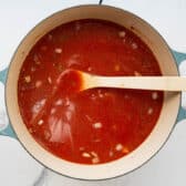 Stirring the tomato broth in a pot of soup.