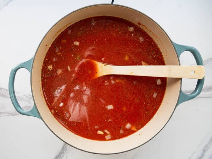 Stirring the tomato broth in a pot of soup.