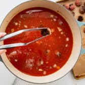 Adding the meatballs back to a pot of soup.