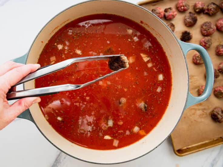 Adding the meatballs back to a pot of soup.