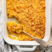 Square overhead shot of scalloped corn in a white dish.