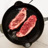 Adding the steak to a hot skillet.