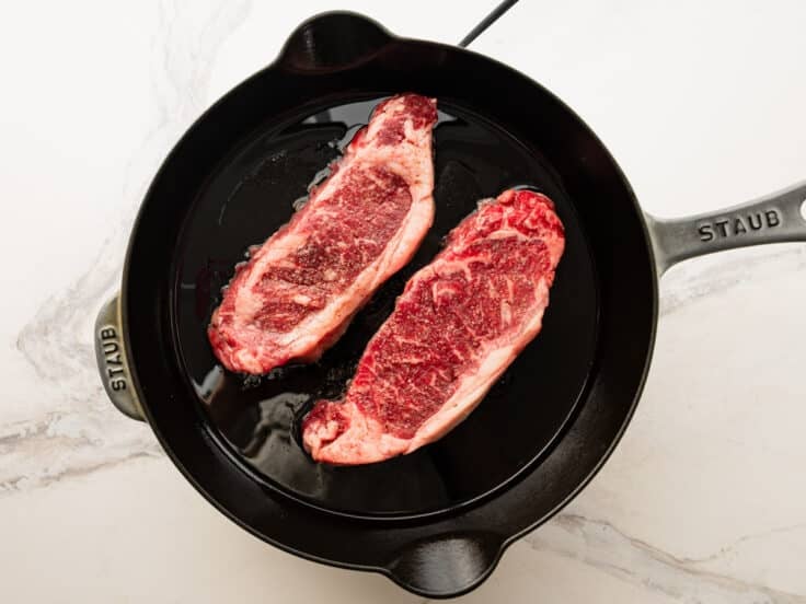Adding the steak to a hot skillet.