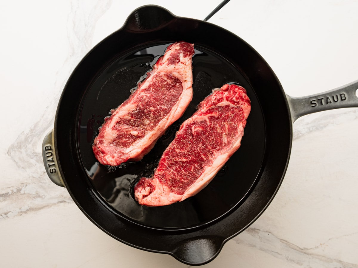 Adding the steak to a hot skillet.