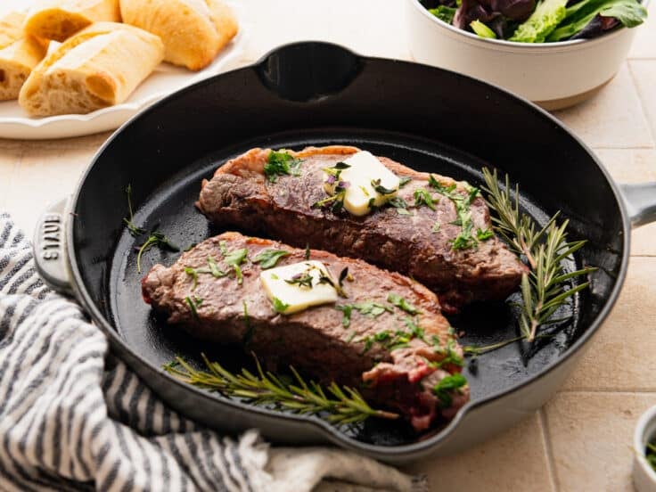 Horizontal side shot of a cast iron skillet steak recipe.