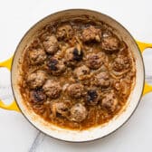 Simmering French onion meatballs with caramelized onions and broth.