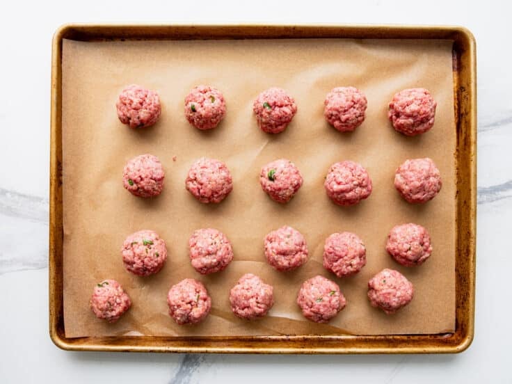 Meatballs on a baking sheet before browning.
