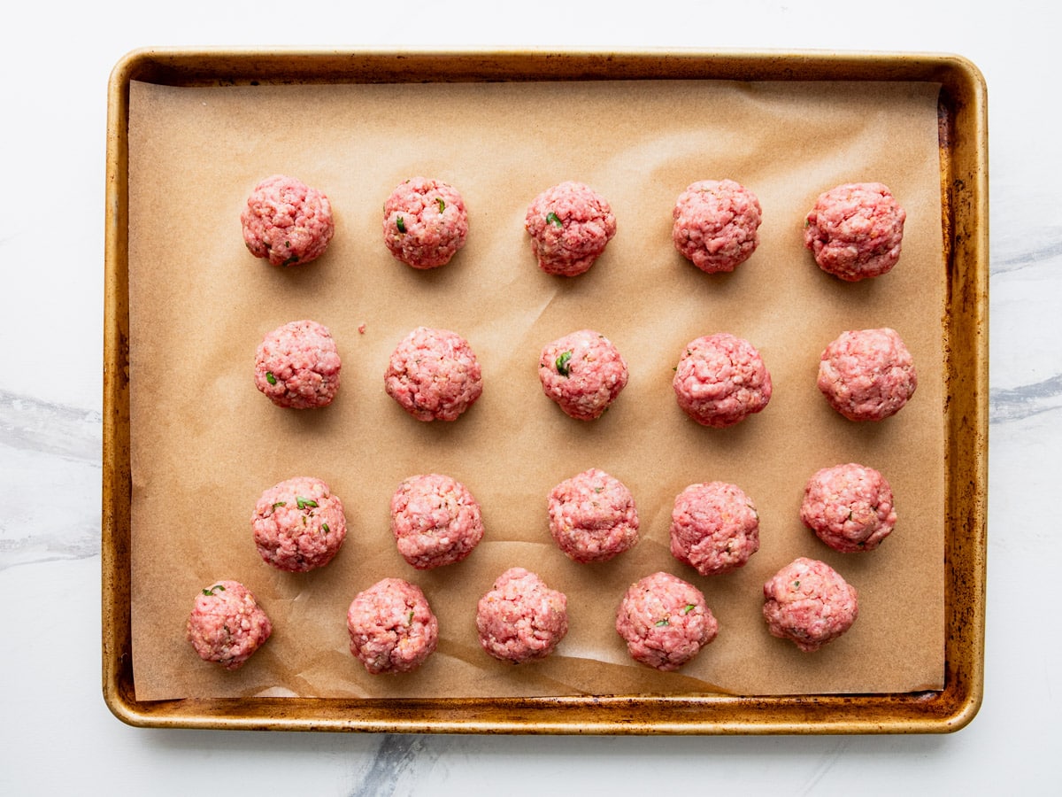 Meatballs on a baking sheet before browning.