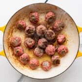 Browning meatballs in a skillet.