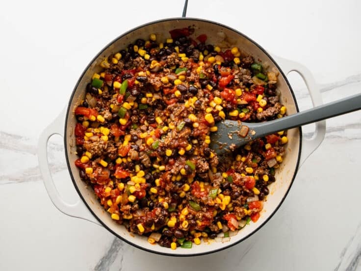 Stirring together the meat filling for a tex mex casserole.