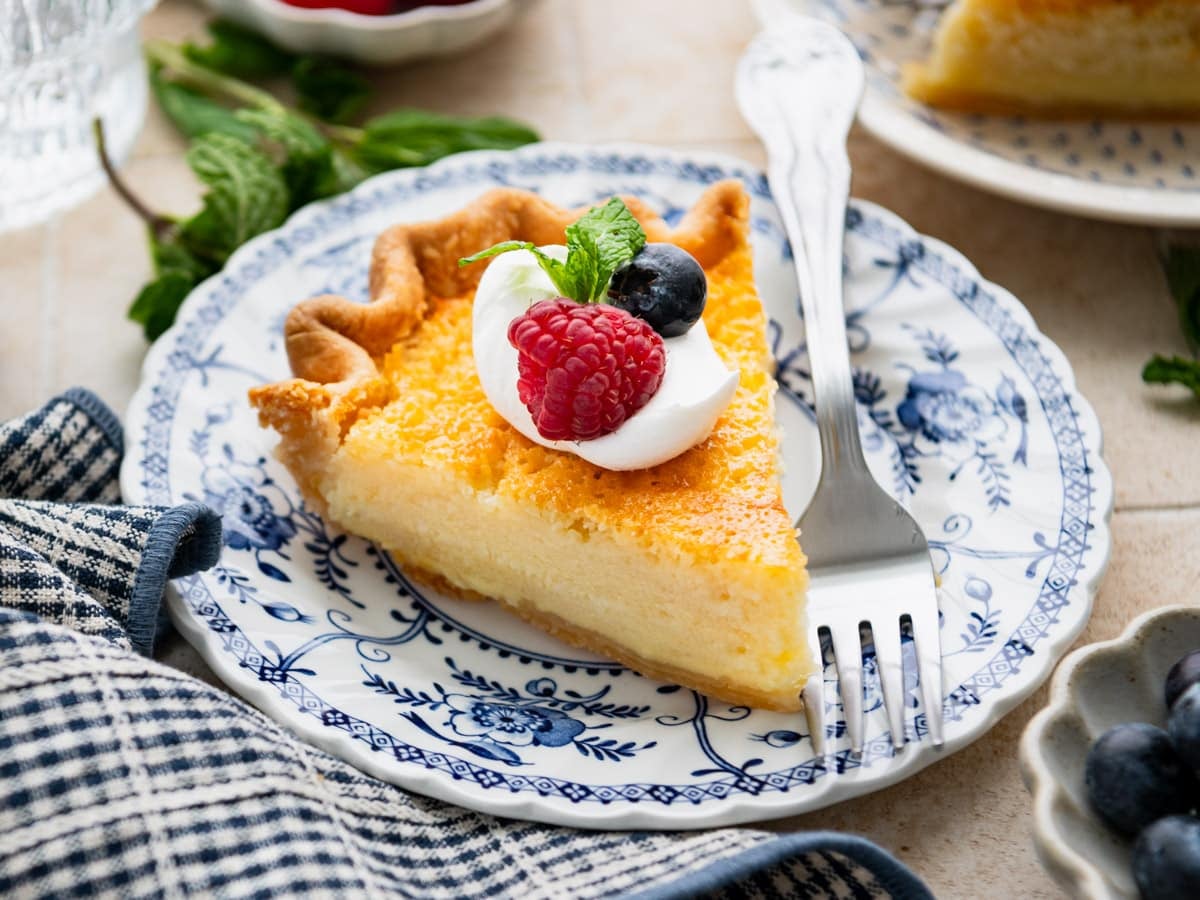 Horizontal side shot of a slice of Southern buttermilk pie on a blue and white plate.