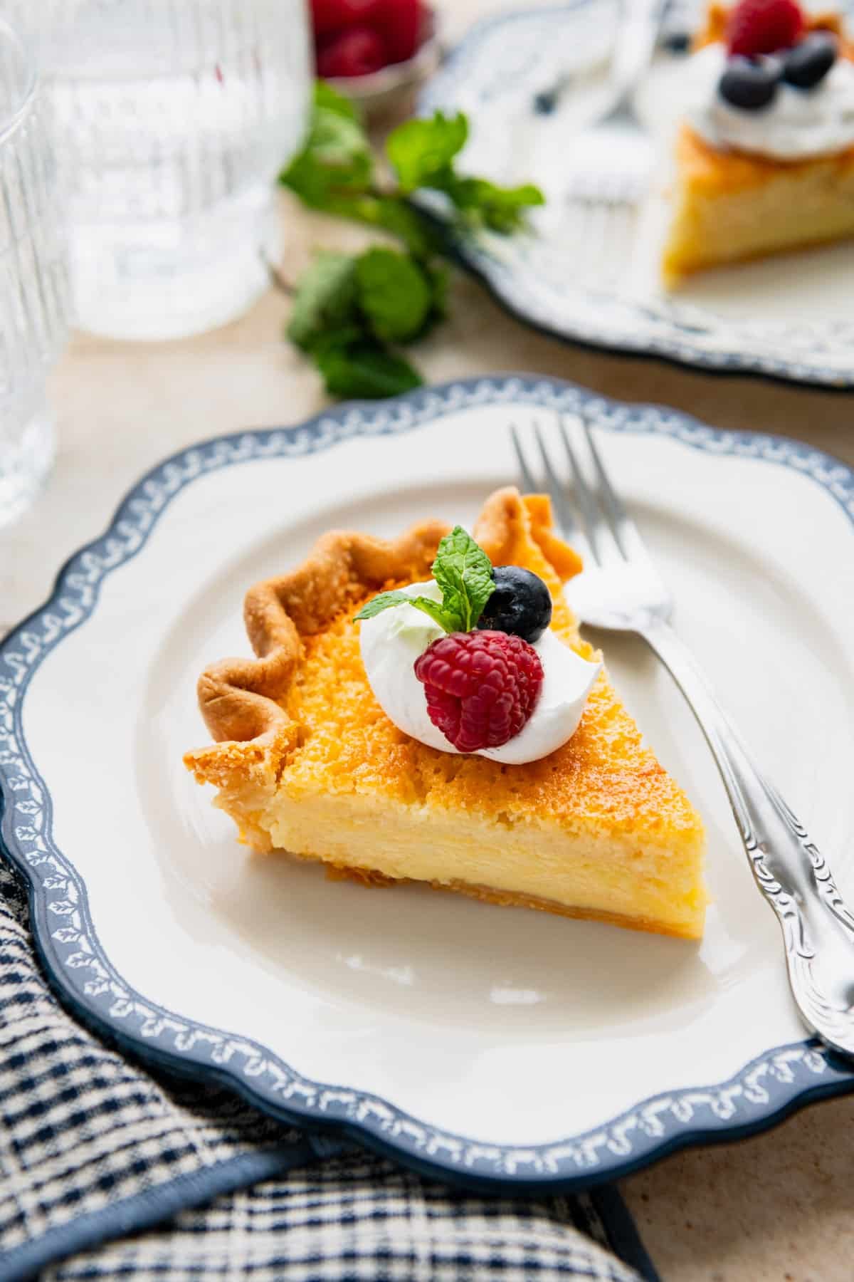 A slice of homemade buttermilk pie on a white plate with blue trim.