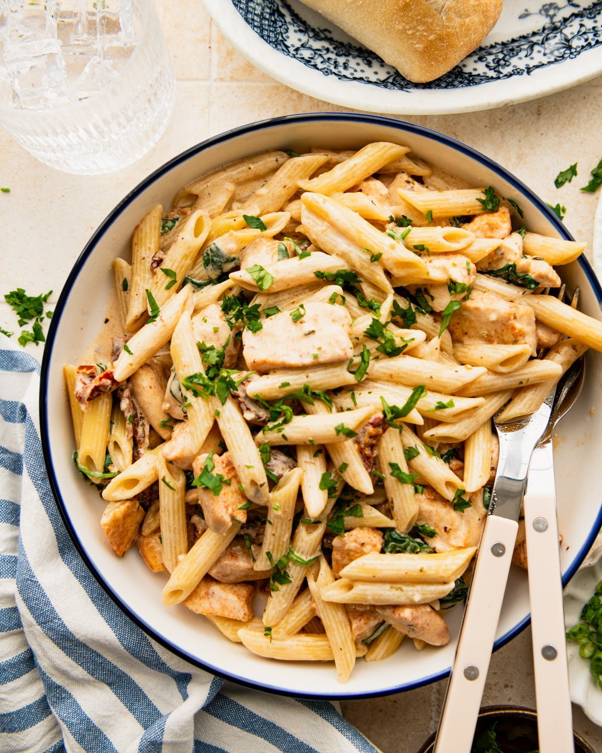 Overhead image of a blue and white bowl full of creamy Tuscan chicken pasta.