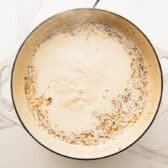 Simmering the cream sauce in a skillet.