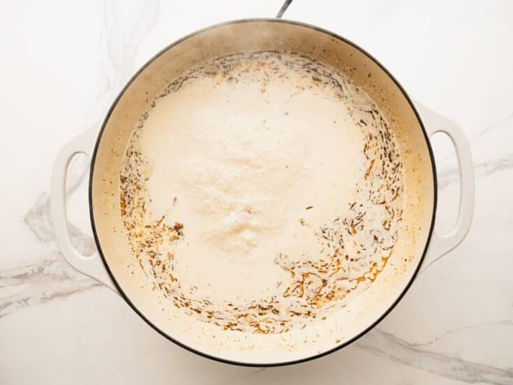 Simmering the cream sauce in a skillet.