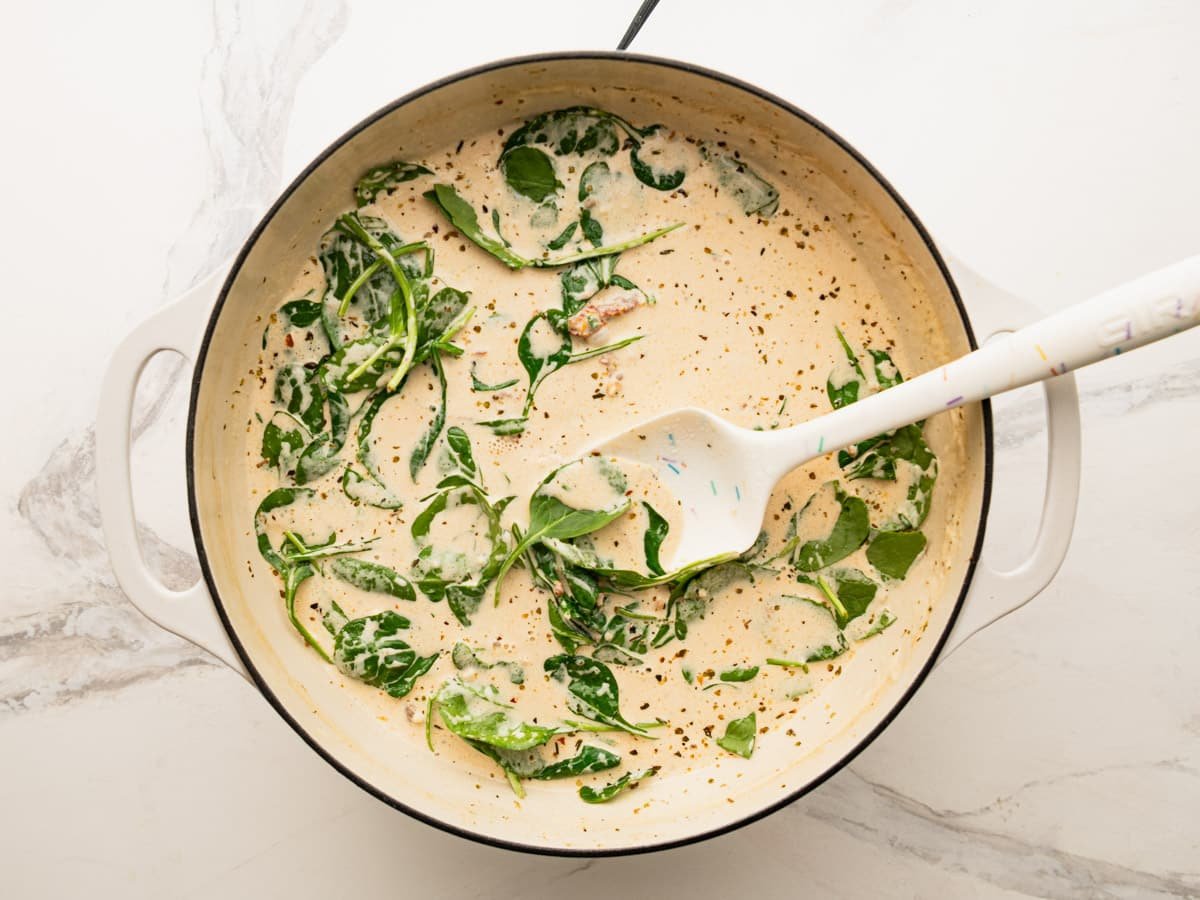 Stirring the spinach into the skillet.