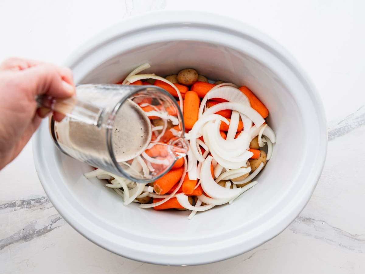 Pouring Guinness into the slow cooker.