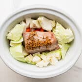 Adding cabbage to the slow cooker.