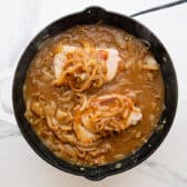 Spooning the onion mixture over the tops of the pork chops.