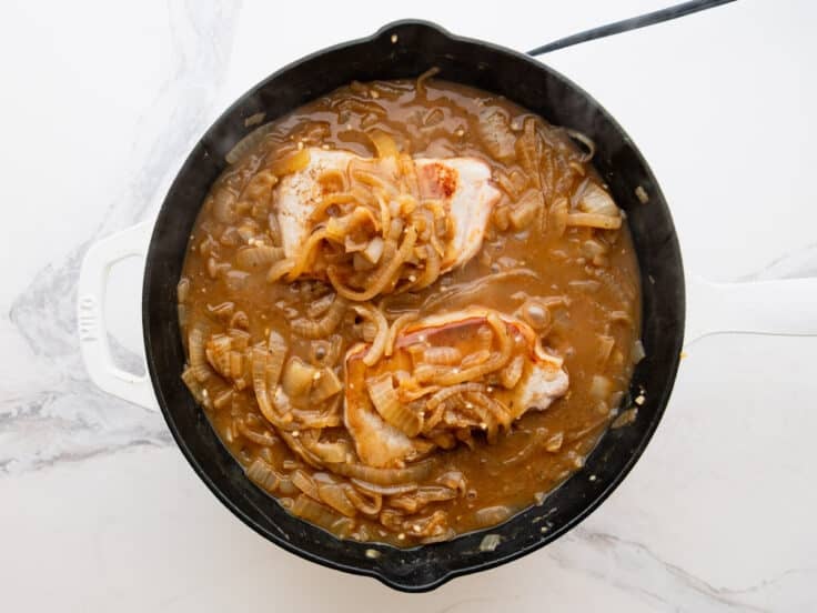 Spooning the onion mixture over the tops of the pork chops.
