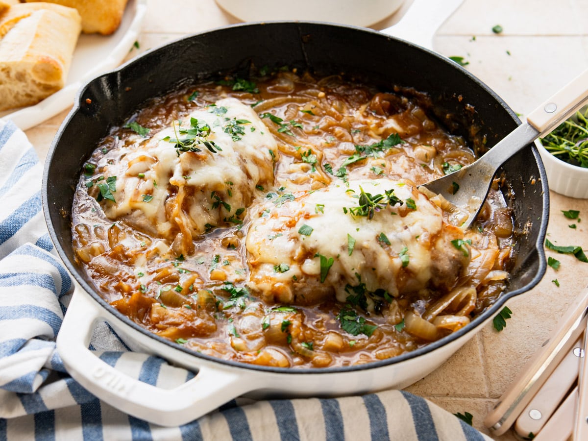 Side shot of a pan of French onion pork chops.