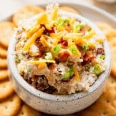 Close up square image of million dollar dip in a bowl with crackers surrounding.