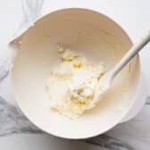 Combining cream cheese and mayo in a white mixing bowl.