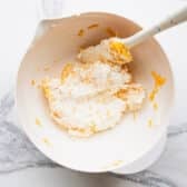 Stirring in grated sharp cheddar cheese.