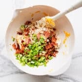 Adding bacon and green onions to the bowl.