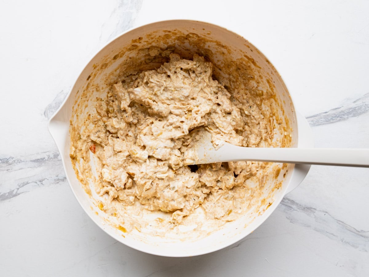 Stirring together the filling for cream cheese chicken enchiladas.