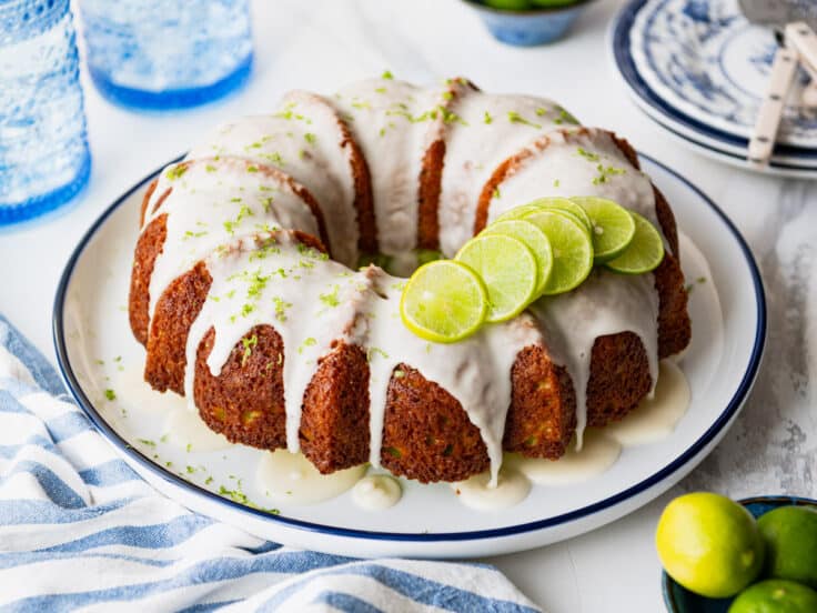 Horizontal side shot of a glazed key lime bundt cake on a serving platter before slicing.