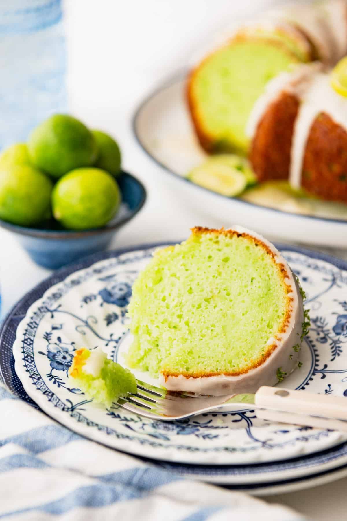 Side shot of a slice of key lime cake on a small blue and white plate.