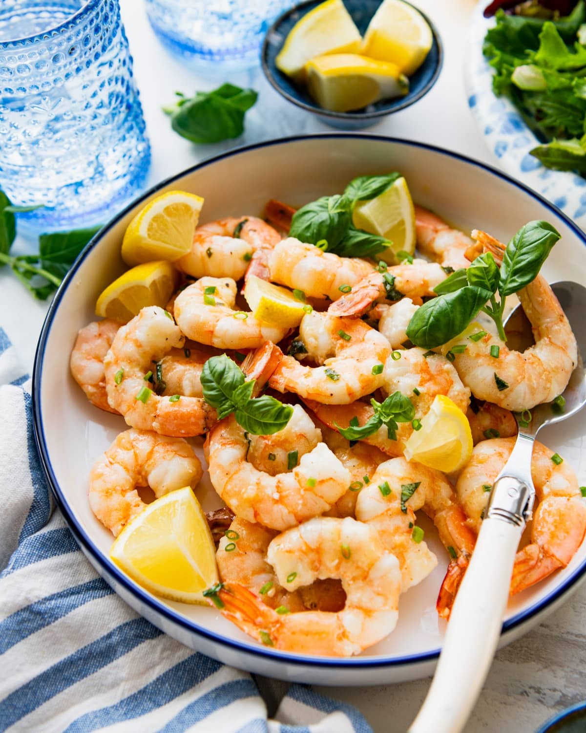 Side shot of lemon garlic shrimp in a bowl with a blue stripe on the rim.