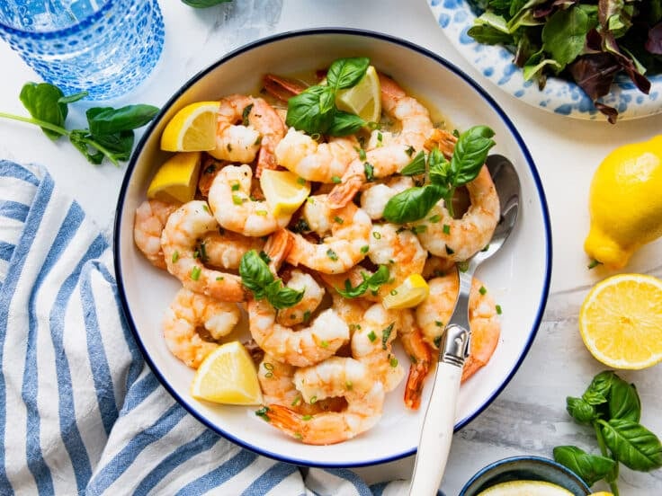 Horizontal overhead shot of a bowl of lemon garlic shrimp with fresh herbs for garnish.