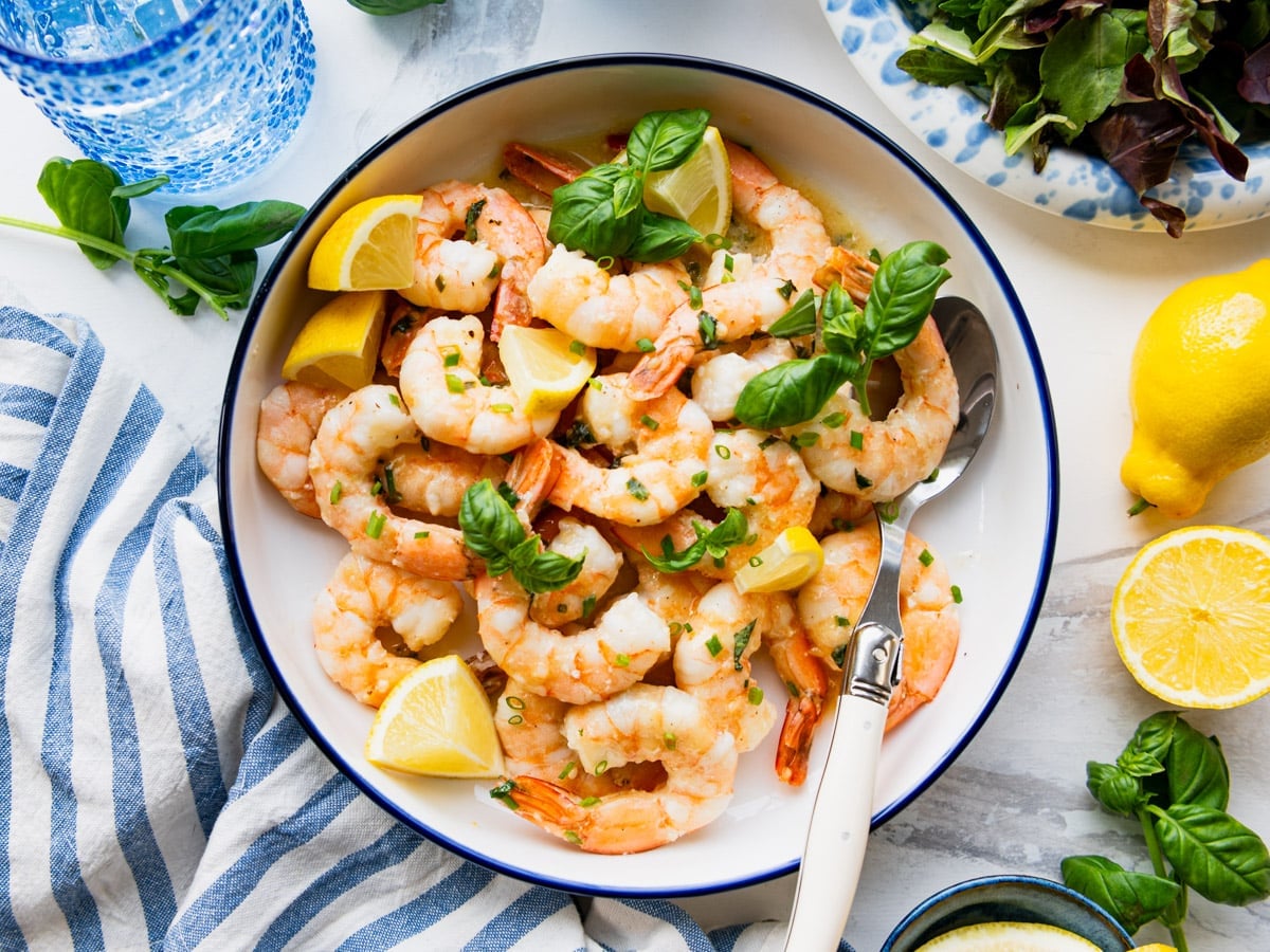 Horizontal overhead shot of a bowl of lemon garlic shrimp with fresh herbs for garnish.
