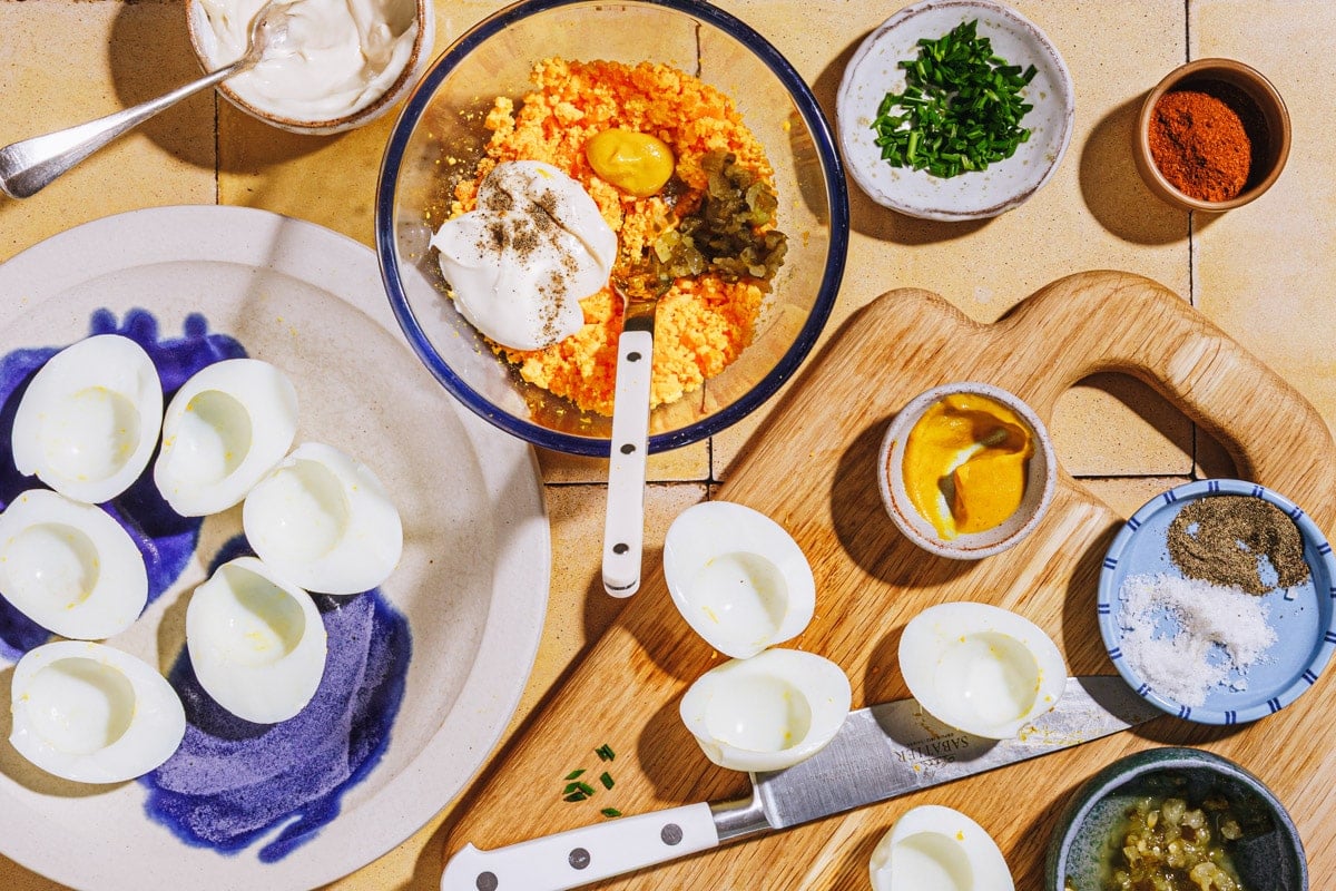 Process shot showing how to make the filling and slice open the eggs for a deviled eggs recipe.