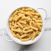 Cooked drained rotini in a colander.