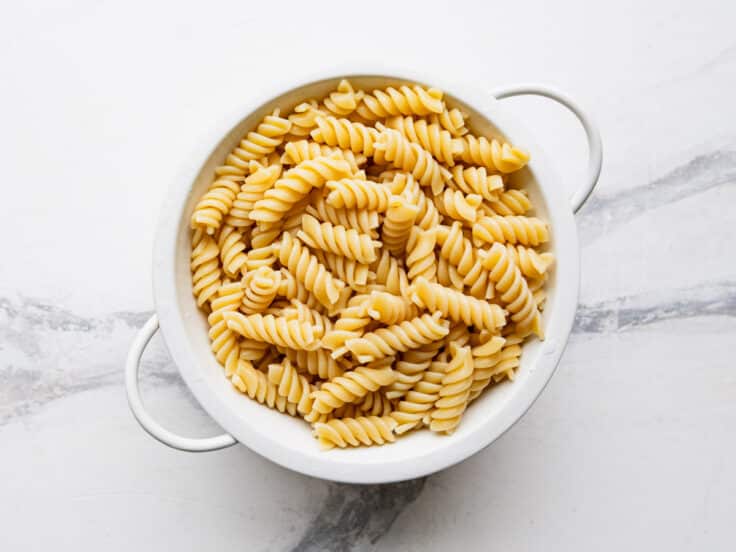Cooked drained rotini in a colander.