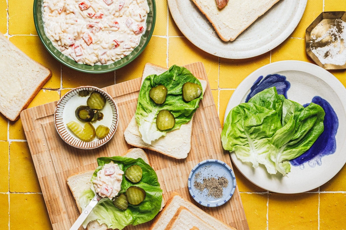 Adding lettuce and pickles to pimento cheese sandwiches.