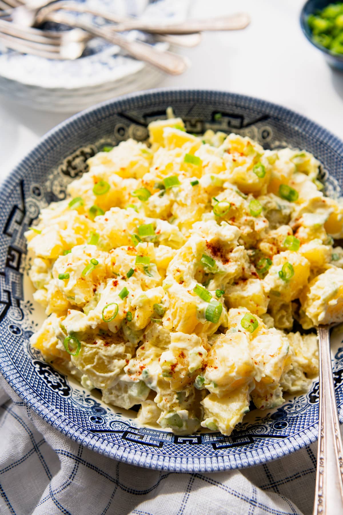 Side shot of a bowl of southern potato salad on a white table.