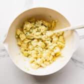 Stirring together diced potatoes with the dressing.