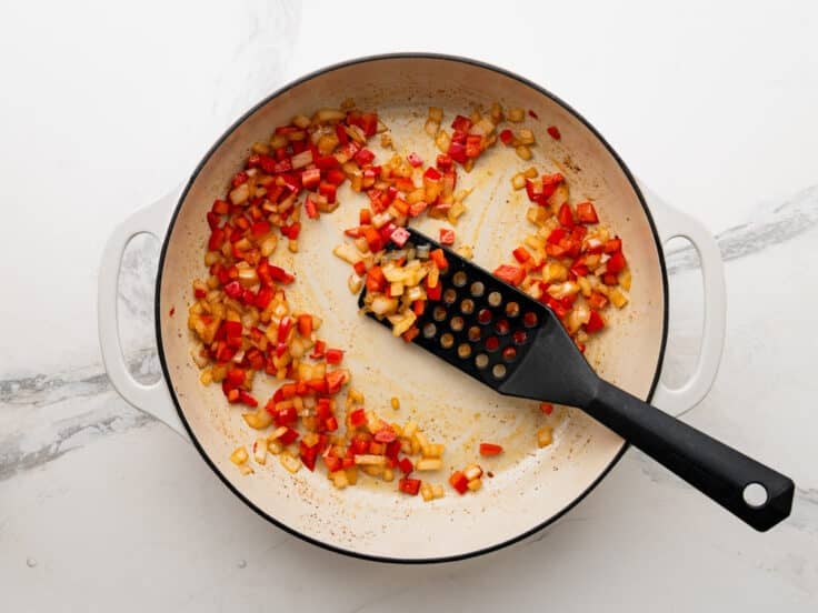 Sauteing bell pepper and onion in a skillet.