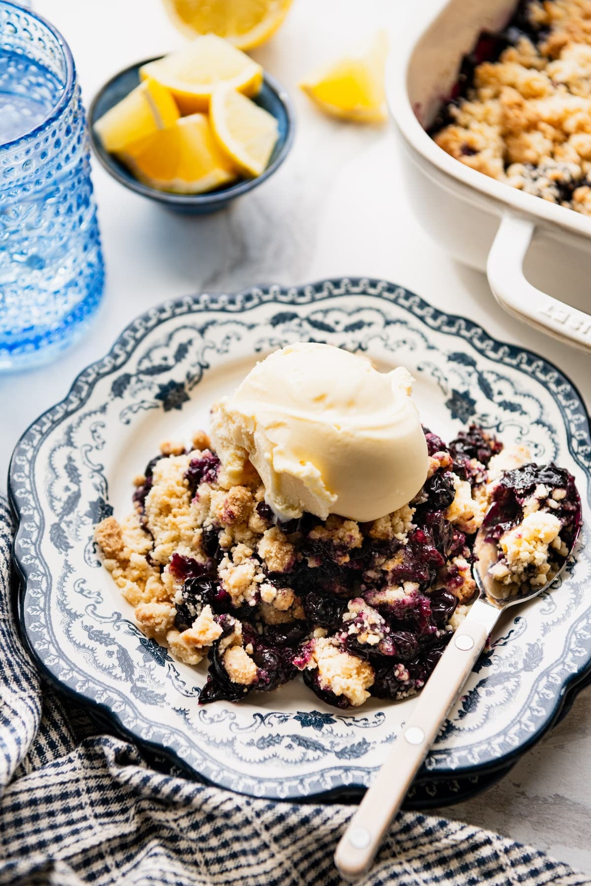 Side shot of blueberry cobbler with cake mix on a plate with vanilla ice cream.