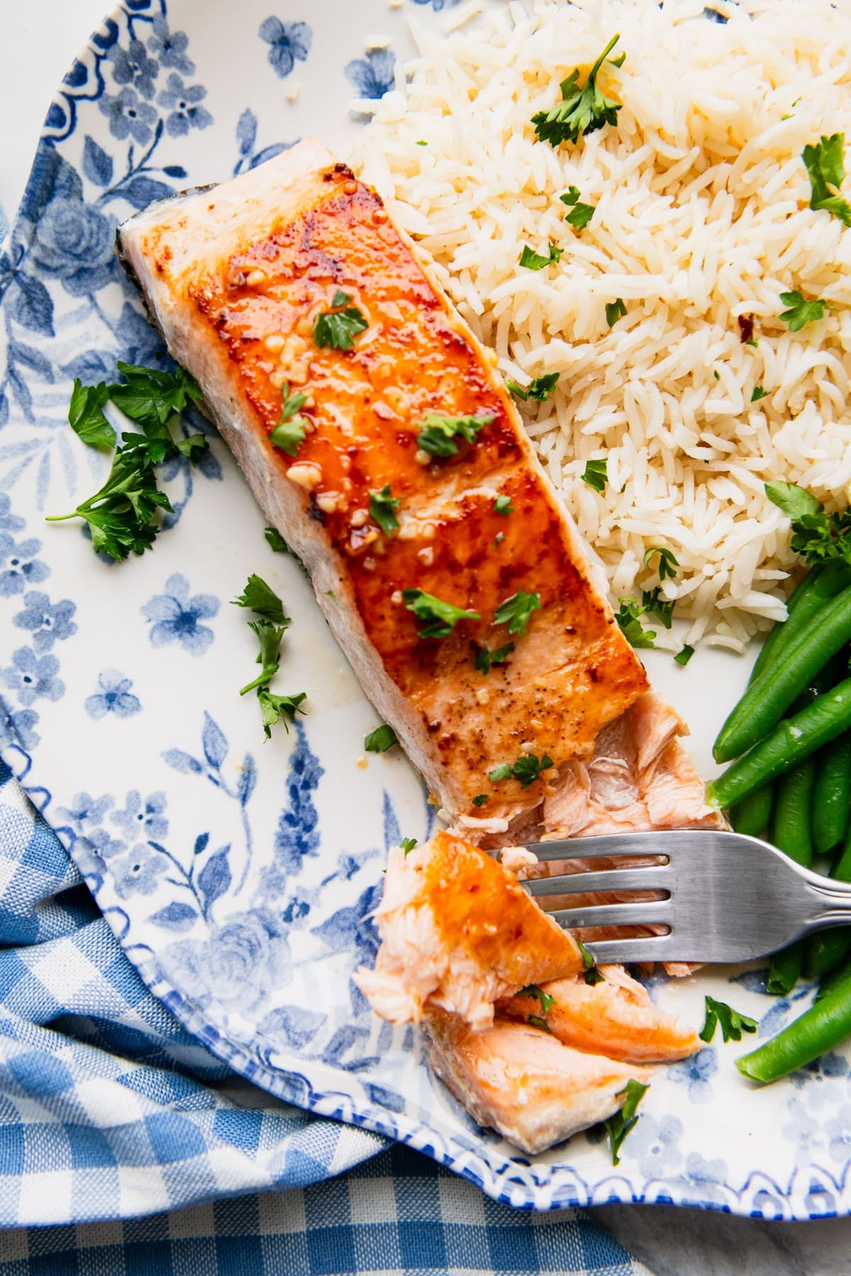 Close overhead shot of a plate of garlic butter salmon with rice and green beans.