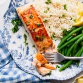 Square overhead shot of garlic butter salmon on a plate with rice and green beans.