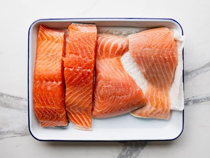 Seasoned salmon fillets on a tray before cooking.