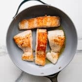 Cooking salmon fillets in a skillet.