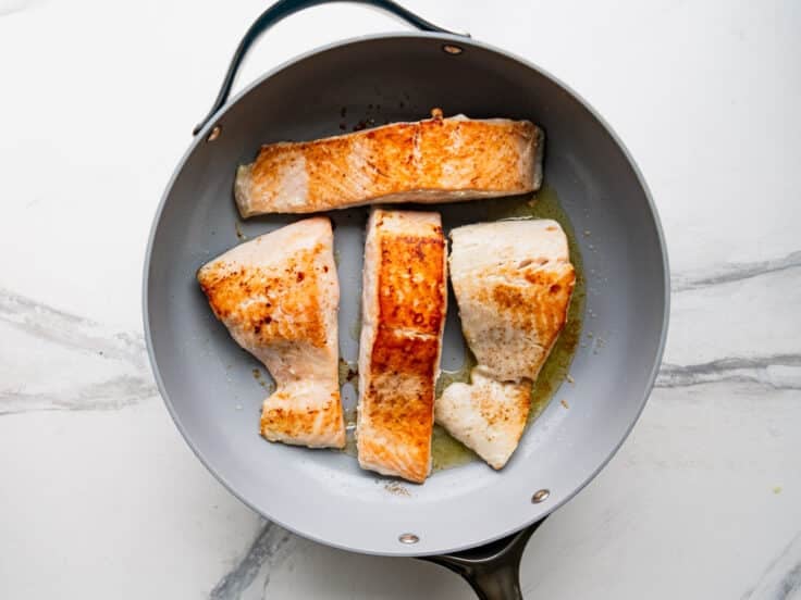 Cooking salmon fillets in a skillet.