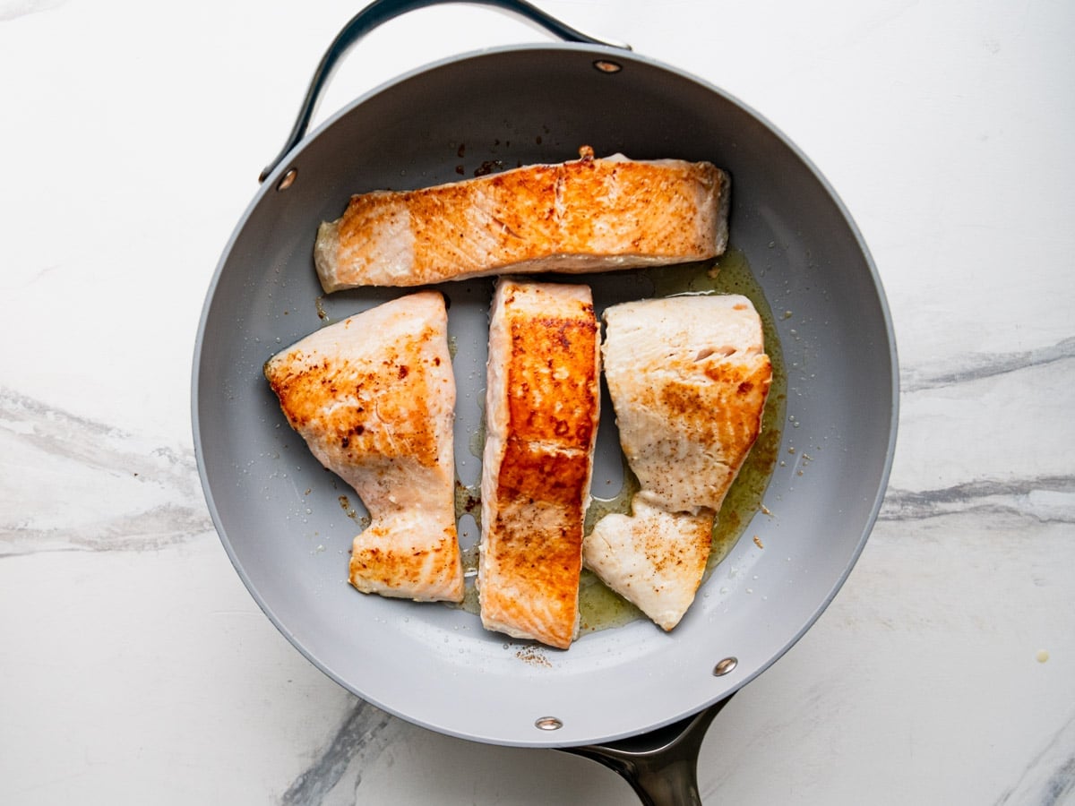 Cooking salmon fillets in a skillet.