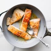 Pan seared garlic butter salmon in a skillet.